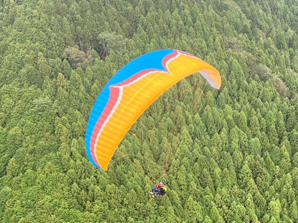 山の上をパラグライダーが飛ぶ