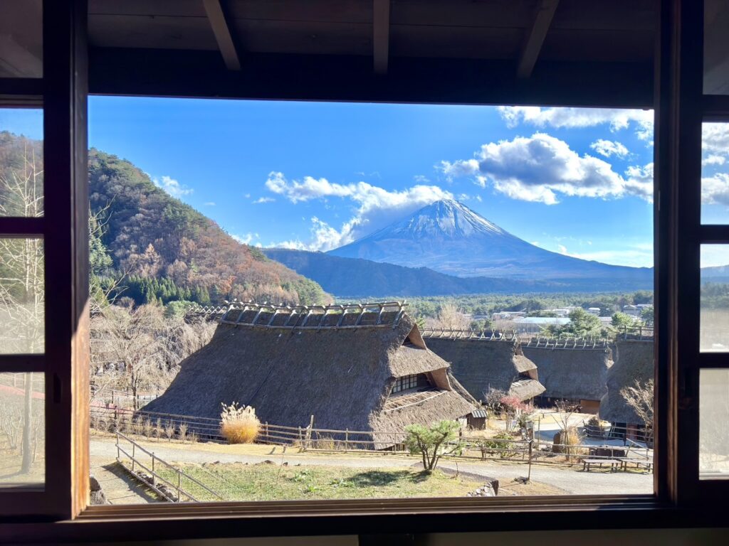 ２階の大窓からみた茅葺き屋根と富士山と青空の美しい風景